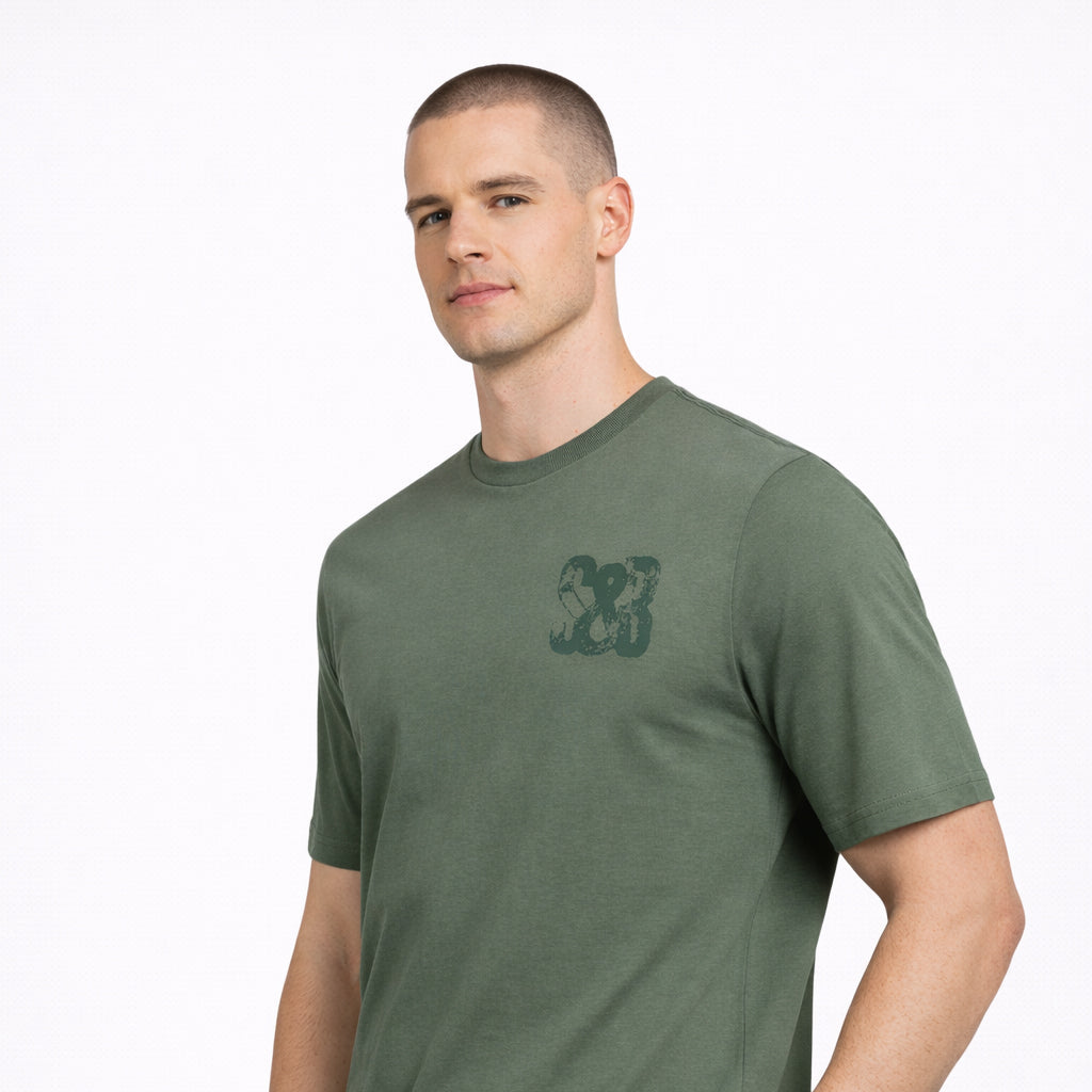 Angled view of Green Bay T-Shirt in green with chest logo worn by model by Sauce & Brown