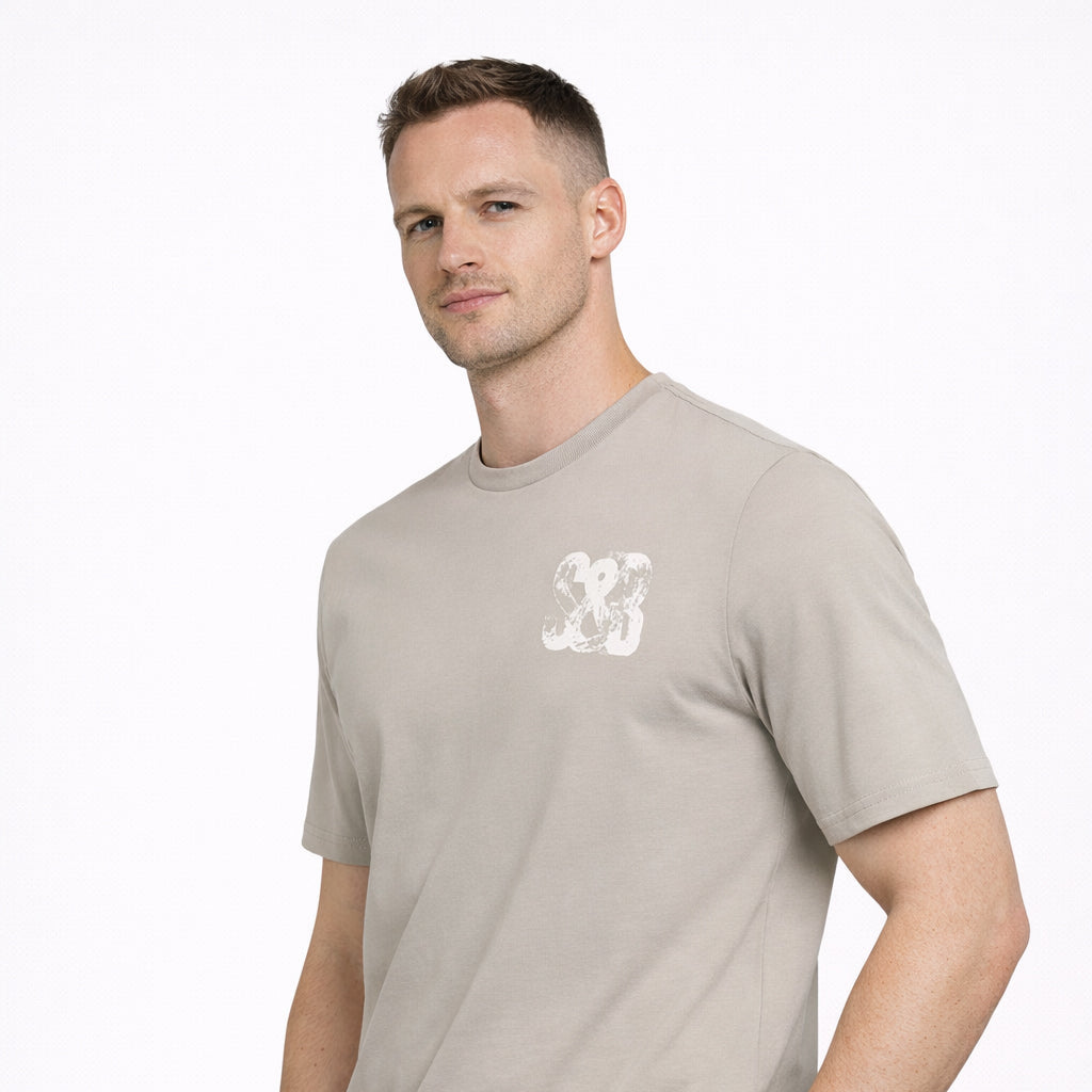 Angled view of Stone Press Printed Tee in stone with logo worn by model by Sauce & Brown