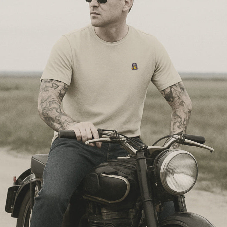Man with tattoos sitting on a vintage motorcycle in a field