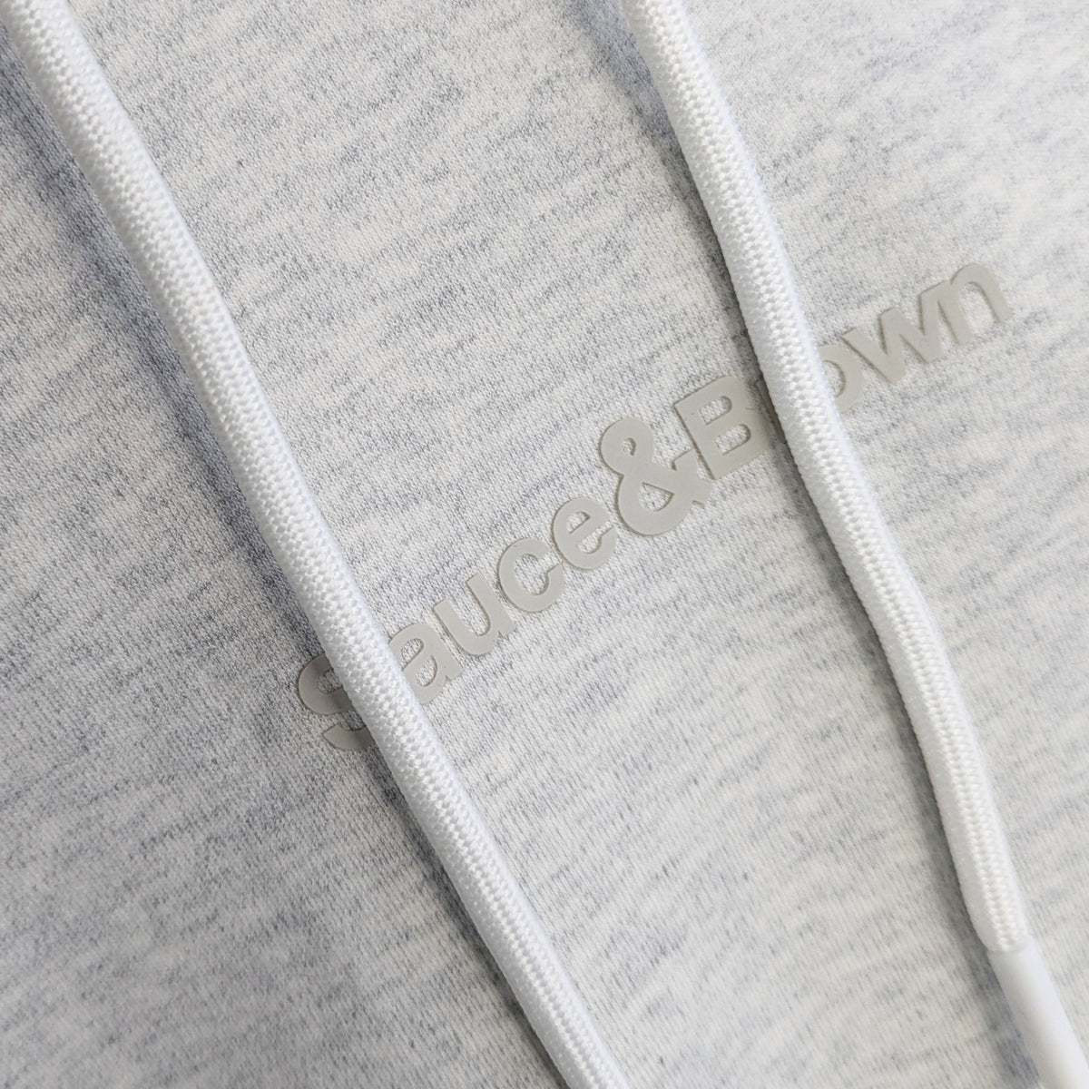 Close-up logo detail on Daub Hoody in light grey by Sauce & Brown