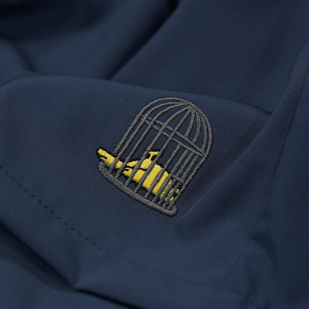 Close-up embroidered logo detail on Tempest Swim Shorts in navy by Sauce & Brown