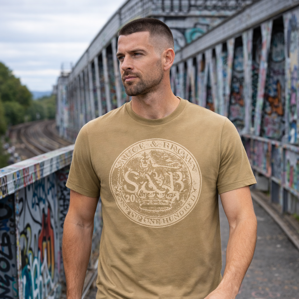 Male model wearing Sauce & Brown Roots faded olive graphic t-shirt walking across graffiti railway bridge